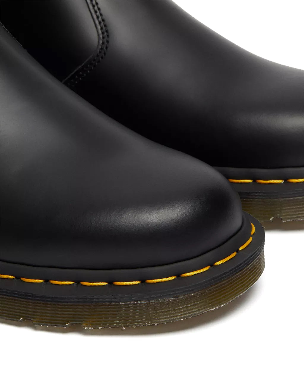 Detail shot of a pair of mid-ankle Dr. Martens black leather chelsea boots.