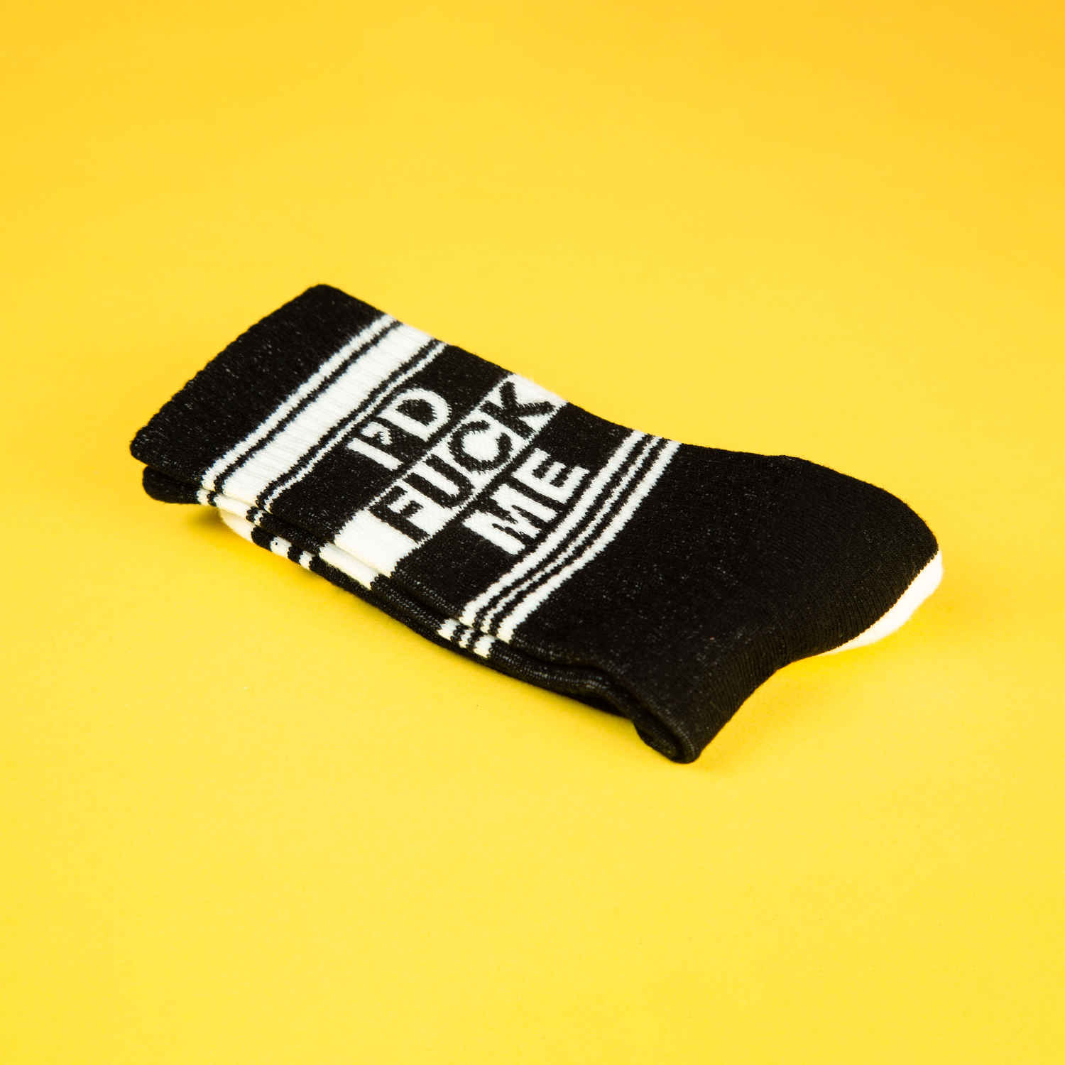 A folded pair of black and white crew socks that read "I'd fuck me."